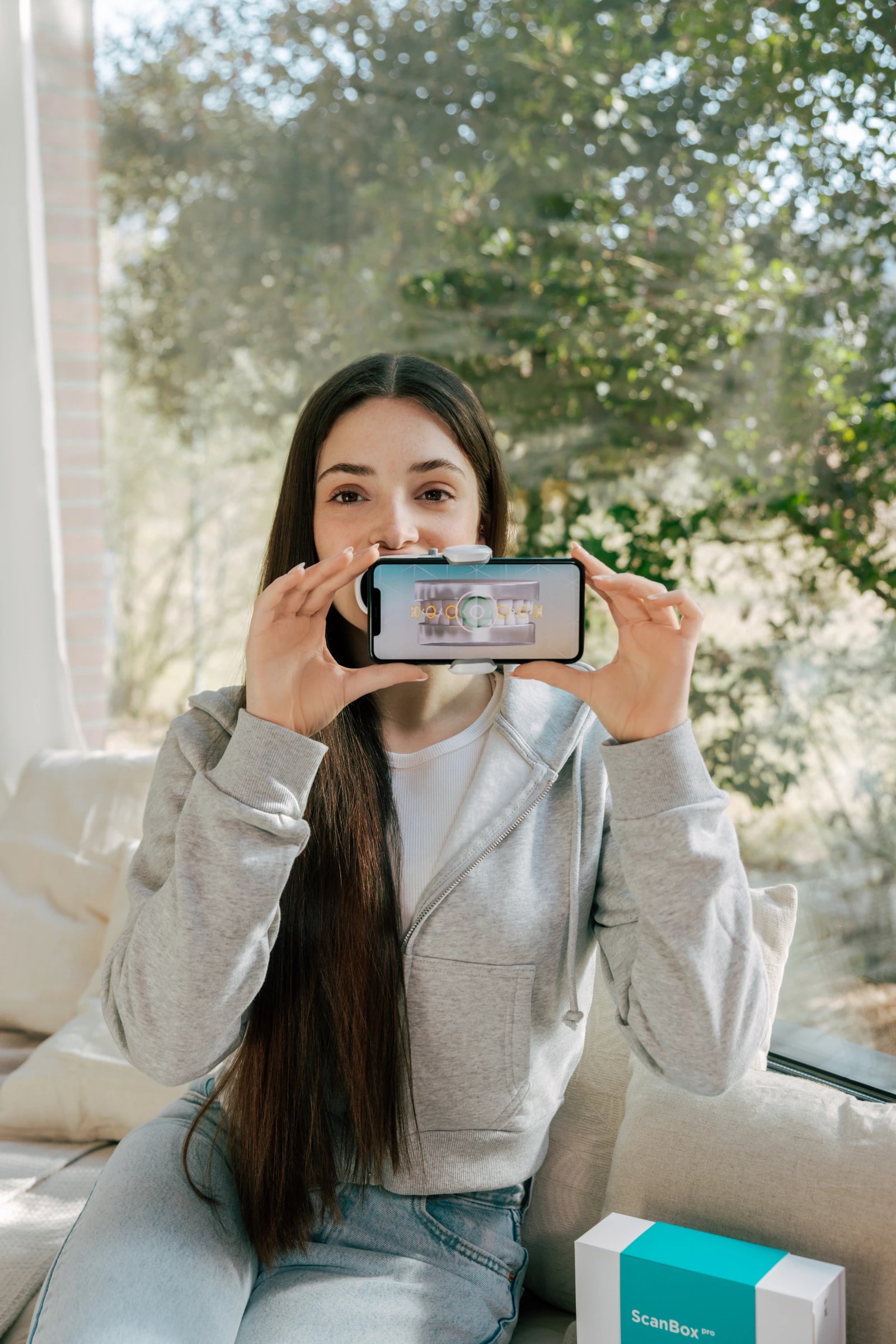 Patientin scannt Zähne mit DentalMonitoring App und ScanBox pro